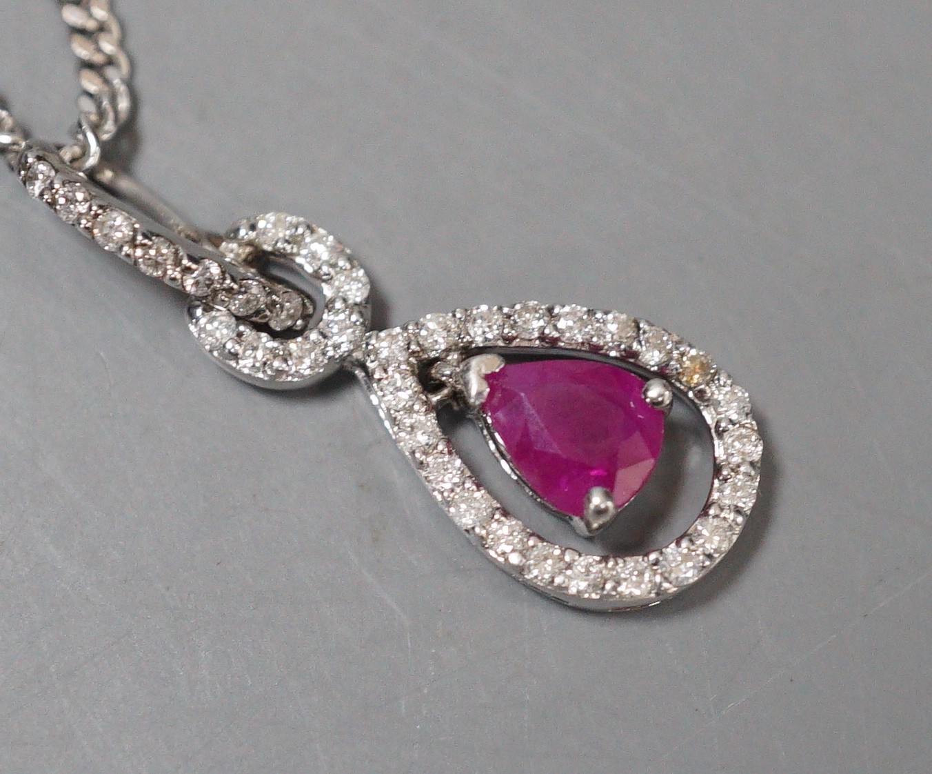 A modern white metal, ruby and diamond chip set pear shaped drop pendant, 20mm, on a 9ct white gold chain, 44cm, gross weight 5.3 grams.